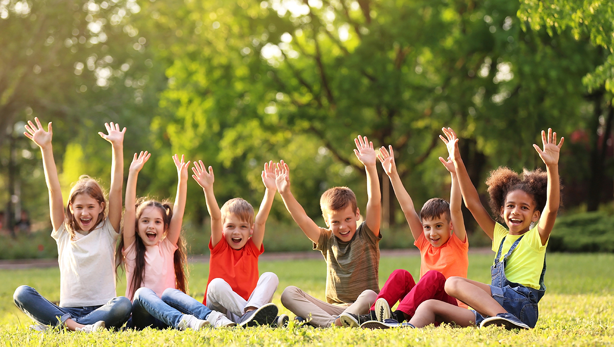 Cute little children sitting on grass outdoors on sunny day